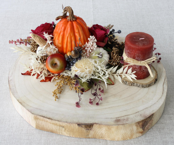 Herbstgesteck Gesteck mit Zierkürbissen und Kerze auf Baumscheibe